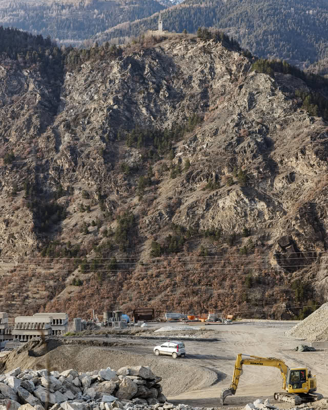 Construction site at the foot of a rocky slope with a sanctuary above